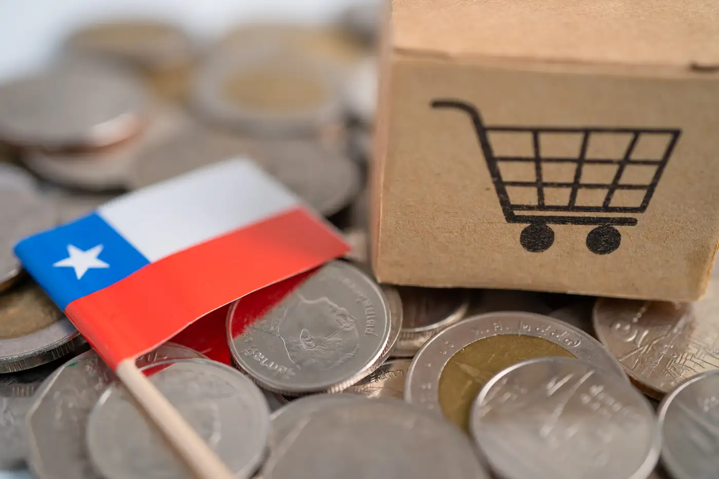 Carro de supermercado y monedas y una bandera de Chile, representando alta inflación en ese país
