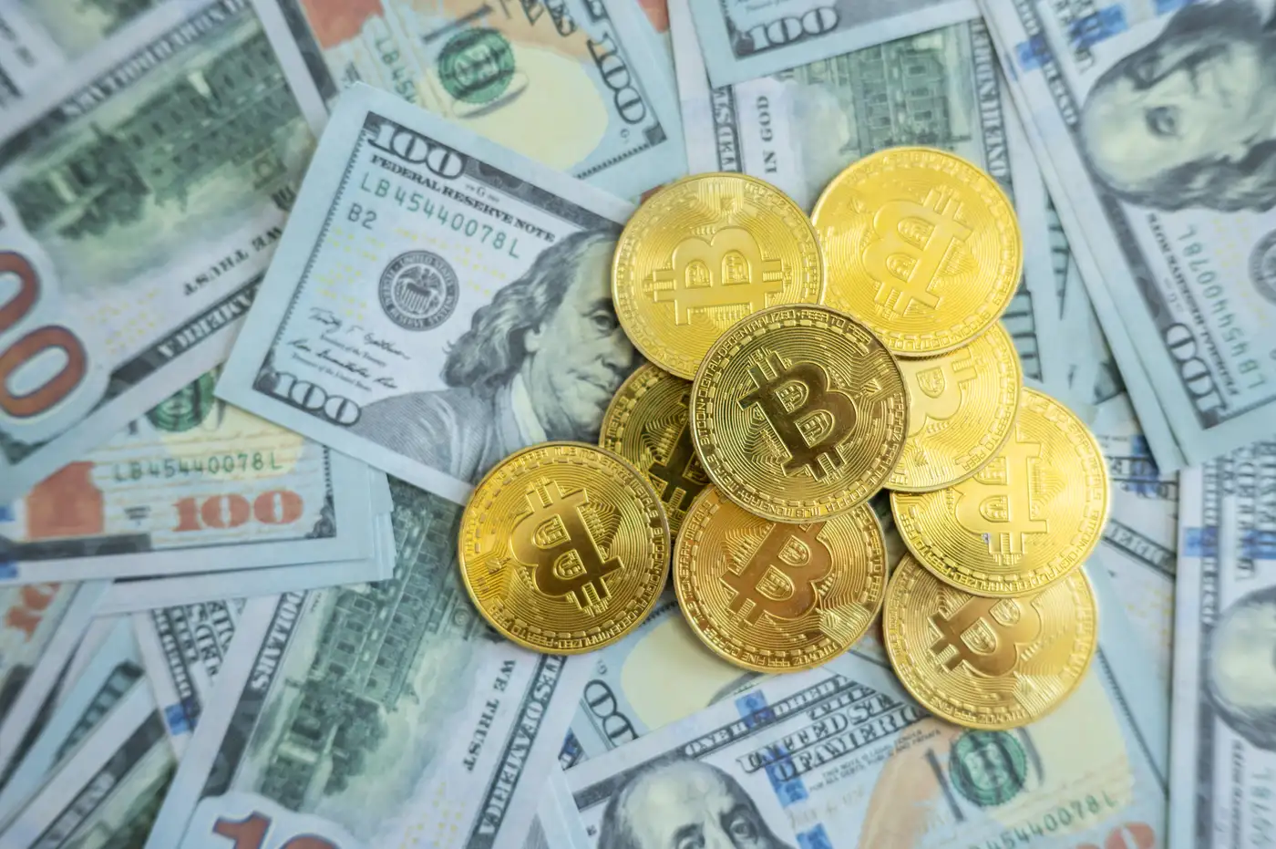 Monedas de bitcoin y oro sobre billetes dólar que representan al competencia entre estos activos